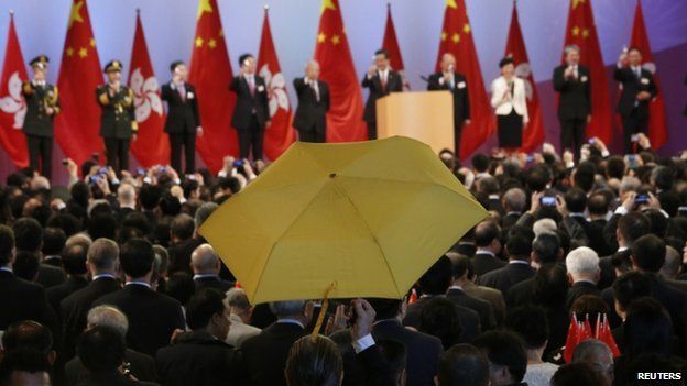 Paul Zimmerman, a district councillor, raises a yellow umbrella as Hong Kong Chief Executive Leung Chun-ying (5th R) addresses guests at a flag raising ceremony in Hong Kong on 1 October 2014