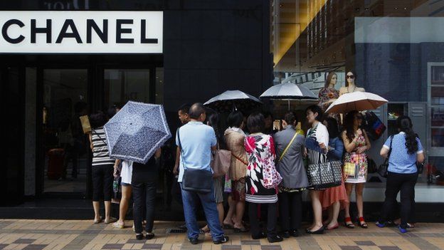 Mainland Chinese tourists wait outside a Chanel store at Hong Kong"s Tsim Sha Tsui shopping district