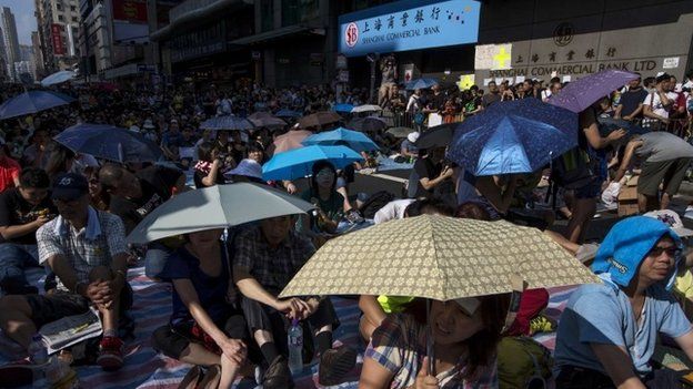Protesters sit under umbrellas at a main street at Mongkok shopping district
