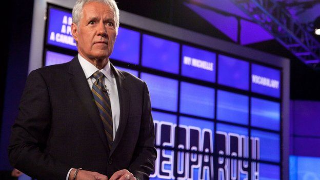 Host Alex Trebek stands on the set of the game show Jeopardy.