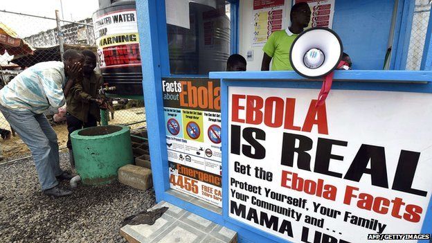 People wash their hands next to an Ebola information and sanitation station raising awareness about the virus in Monrovia on September 30