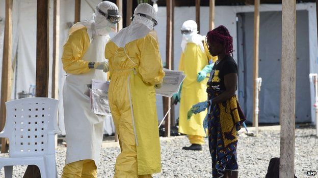 Health workers in protective suits treat a woman and her two childrenat MSF's (Doctors Without Borders) Ebola treatment centre in Monrovia 1 October 2014