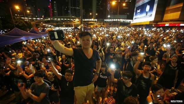 Protesters turn on their mobile phone flashlights as they block an area outside the government headquarters building in Hong Kong on 1 October 2014