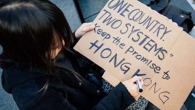 Woman writes a sign supporting Hong Kong at a protest in Stockholm, Sweden (1 Oct 2014)