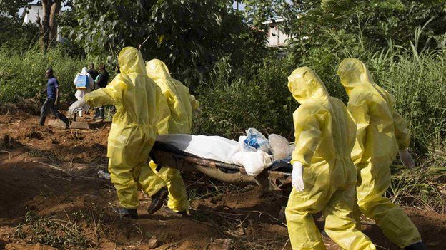 A burial team wearing protective clothing prepare the body of a person suspected to have died of the Ebola virus for interment, in Freetown September 28, 2014