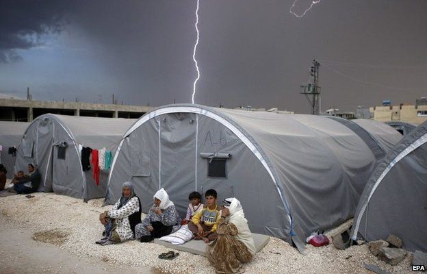 Lightning strikes as a Syrian refugee family sit beside their tent in Suruc district, near Sanliurfa, in Turkey (2 October 2014)