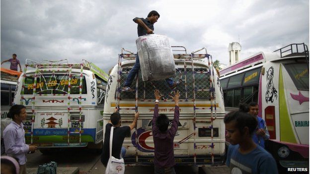 People load their luggage on top of a long distance bus heading to their village for Dashain, Hinduism's biggest religious festival, at the bus station in Kathmandu 24 September 2014