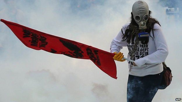 A protester holds a flag as police use tear gas and water cannon in Ankara against demonstrators who are opposed to what they say is Turkish inaction over the IS advance on Kobane (7 October 2014)