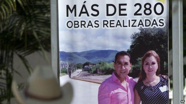 A man looks at a sign promoting city projects featuring the city mayor and his wife, Jose Luis Abarca and Maria de los Angeles Pineda Villa, outside the municipal headquarters in Iguala on 7 October, 2014.