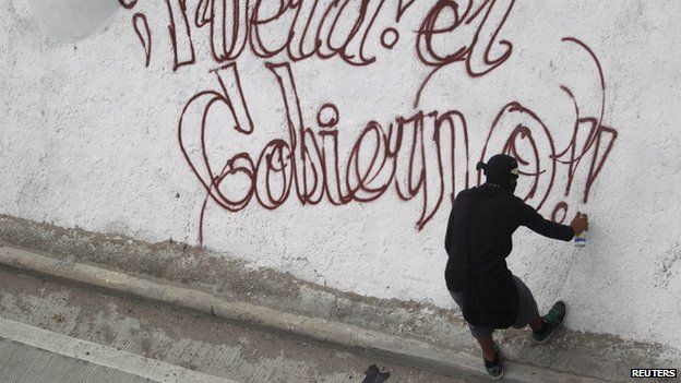 An activist sprays graffiti which reads "Out the Government", during a demonstration by activists in Chilpancingo, in the Mexican state of Guerrero (8 October 2014)