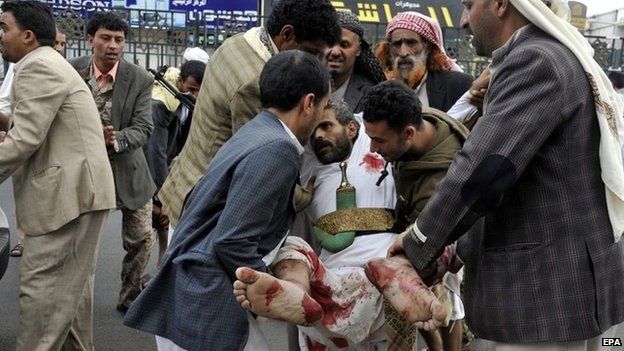 Man carry a man injured in a suicide bomb attack in Yemen's capital, Sanaa (9 October 2014)