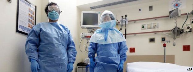 Bellevue Hospital nurse Belkys Fortune, left, and Teressa Celia, Associate Director of Infection Prevention and Control, pose in protective suits in an isolation room, in the Emergency Room of the hospital, during a demonstration of procedures for possible Ebola patients