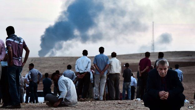 Kurdish people stand on a hill at the Turkish-Syrian border in the south-eastern village of Mursitpinar, Sanliurfa province, on 9 October 2014.