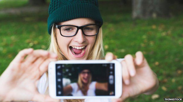 Girl in a hat and glasses grinning for a selfie