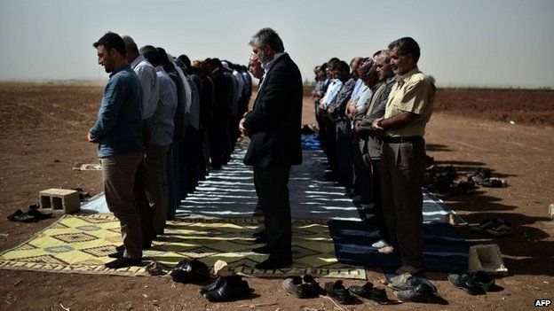 Syrian and Turkish Kurds pray during Friday prayers at the Turkish-Syrian border on 10 October 2014