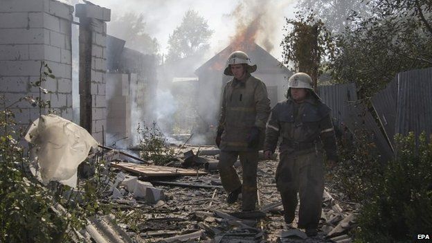 Firemen walk past a damaged building after shelling near of Donetsk's International Airport, Ukraine, 9 October 2014