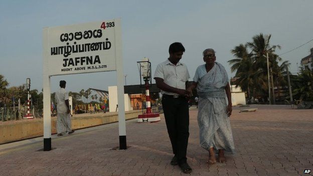 An elderly Sri Lankan ethnic Tamil woman is helped by a man as they walk along a platform at the Jaffna railway station in Sri Lanka, 12 October 2014