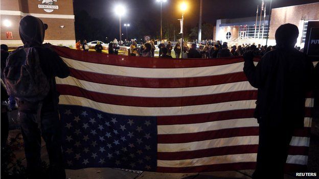 Protestors carry a US flag upside down at Ferguson protests