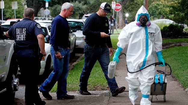 A man in protective clothing walks near the apartment of a second Dallas-area Ebola victim.