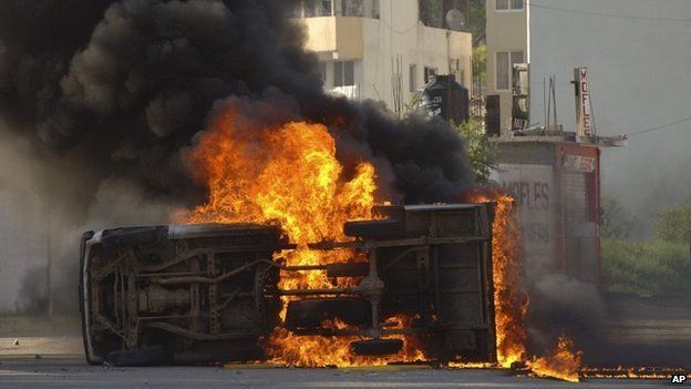 An overturned car burns after it was set on fire by protesting college students outside the Guerrero state capital building in Chilpancingo, Mexico - 13 October 2014
