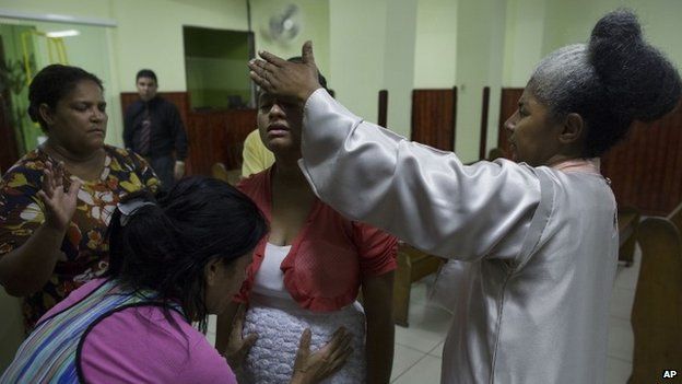 Two women pray for a young pregnant woman after a service in the Assemblies of God Ministry of Restoration, in the Coreia shantytown, Rio de Janeiro (September 2014)