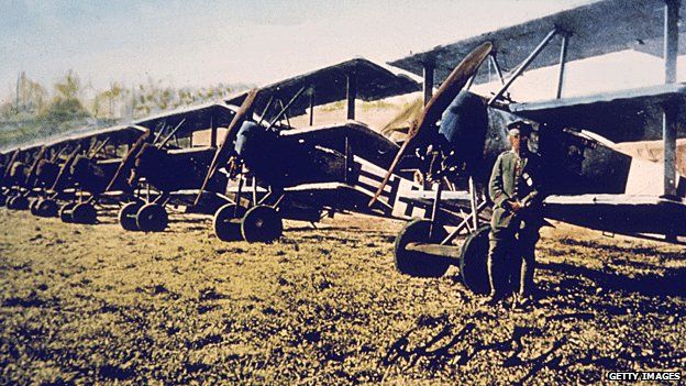 A German soldier stands by a row of Fokker DR-1 tri-planes on an airfield in Germany