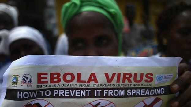 Woman holding up Ebola information poster