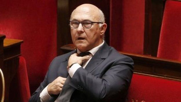 French Finance Minister Michel Sapin adjusts his tie at the start of budget debates in the National Assembly. Photo: 14 October 2014