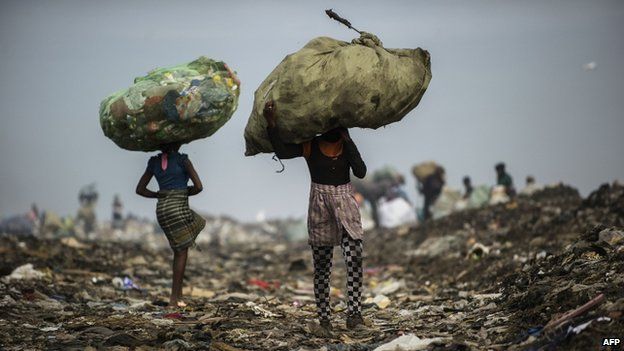 Girls carry bags of plastic items and tins as rubbish pickers sift through garbage at the Maputo municipal garbage dumping site in Maputo, Mozambique (October 2014)