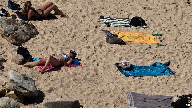 People sunbathe at Bondi beach in Sydney on 4 January, 2013