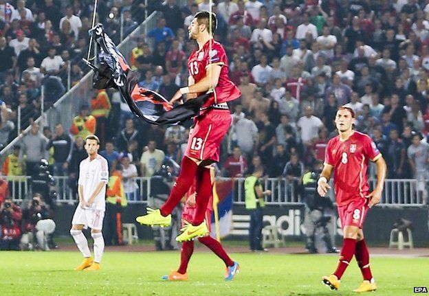 Serbia player Stefan Mitrovic grabs the banner at the stadium in Belgrade, 14 October