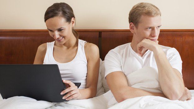 Woman on internet while man looks bored