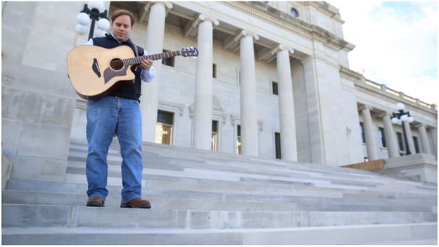 Politician with guitar on state capitol steps in Arkansas