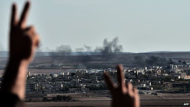 Kurds react as they watch smoke rising from the Syrian town of Kobane during fighting between Islamic State militants and Kurdish fighters (15 October 2014)