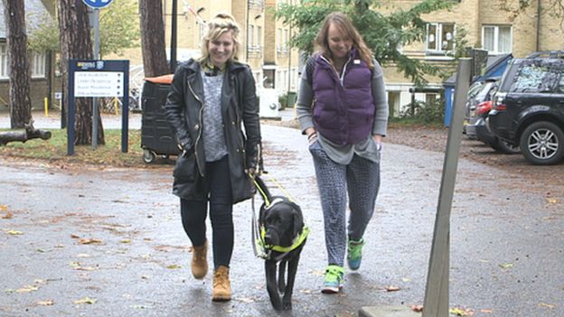 Molly with her guide dog and a friend walking outside her university