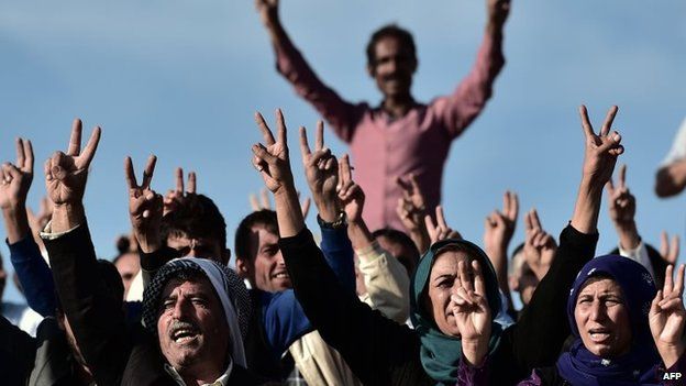 Kurdish people shout slogans while standing upon a hill opposite the Syrian town of Kobane, also known as Ain al-Arab, in the south-eastern village of Mursitpinar, Sanliurfa province, 15 October 2014