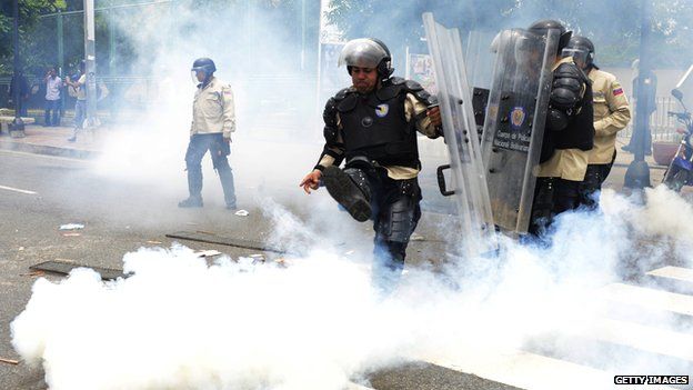 A policeman kicks away a tear gas canister in Caracas, May 2014