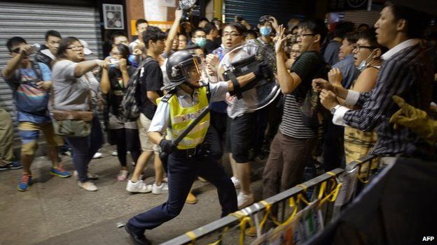 A policeman holding a baton advances towards pro-democracy protesters as they clash on a street in the Mong Kok district of Hong Kong early on 19 October 2014