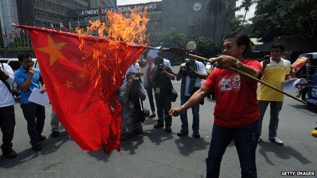 An anti-China activist burns a Chinese flag during a protest in front of the Department of Foreign Affairs building in Manila on 27 July, 2012