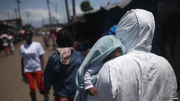 Liberian health worker carries a baby suspected of having contracted Ebola from his family members