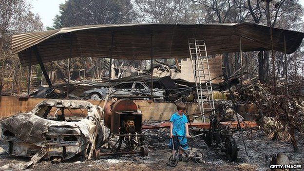 A boy inspects the remains of his grandparent's home that was destroyed by bushfire on 21 October, 2013 in Winmalee, Australia