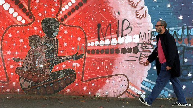 Gumubanga Djunguti Aborigine Grahame Silva walks past a mural by Jim Simons from The Block, part of the first land grant to Aborigines, in Sydney - 1998
