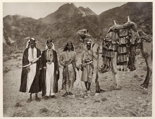Photo taken in the 1880s by Meccan photographer Abd al-Ghaffar. It shows Sharif Yahya (second from right), a close relative of the ruler of Mecca, with two lesser noblemen (left). Yahya's slave (far right) holds a long-barrelled rifle, and all four men wear traditional weapons, known as "janbiya" – three are long scimitars, one is a shorter, curved dagger.
