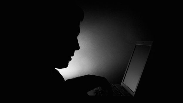 A silhouette of a man using a laptop