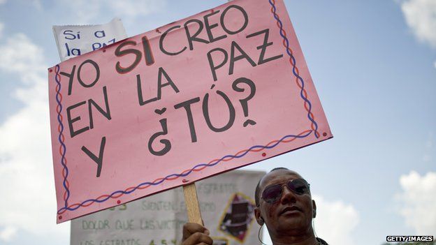 A Colombian man holds a sign reading 'I do believe in Peace and you?' on 9 April, 2014.