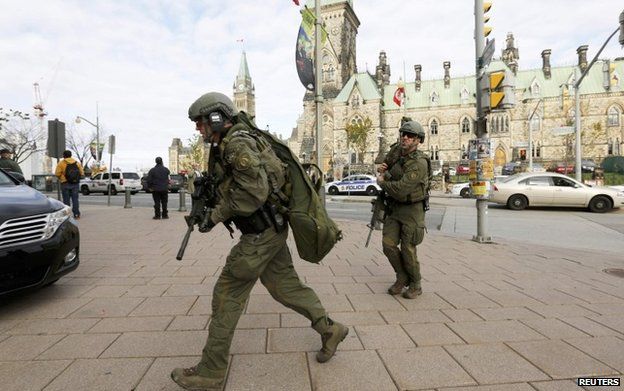 Armed RCMP officers head towards the Langevin Block on Parliament Hill