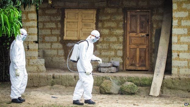 A healthcare sprays disinfectant in Port Loko Community, Freetown, Sierra Leone, 21 October 2014
