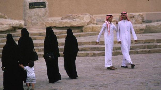 Riyadh family in traditional dress, Saudi Arabia. Men dressed in white and women in black dress