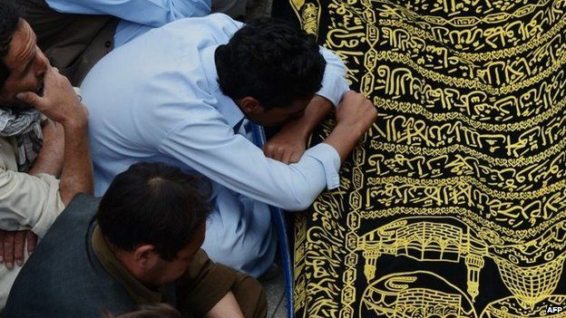 Pakistani Shiite Muslim mourners sit beside the coffin of a community member killed in an attack by gunmen on a passenger mini bus