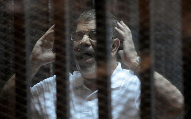 Egypt's ousted President Mohammed Morsi inside the defendant's cage at his trial